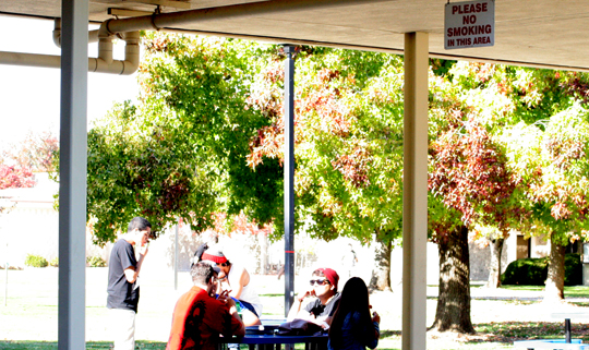 Yuba College students having a smoke break right outside the campus center nearby a sign that prohibits smoking in the area | Photo by Capa Lo