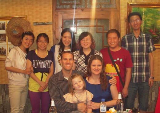 Professor Smith and his family seated at a dinner table; among them, students pose for the camera.
