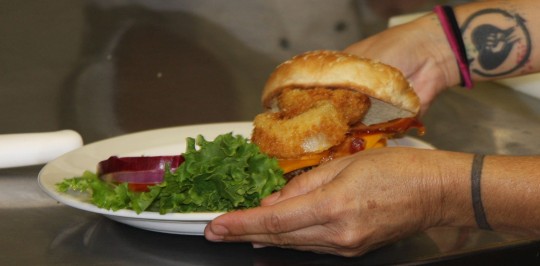 A student plating a western bacon cheeseburger.