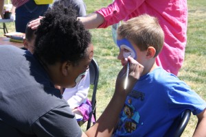 Activities Coordinator Kapri Karcher face paints Sonic the Hedgehog on a child for the "Planting A Seed For Children's Growth" event at POW/MIA Edgewater Park.