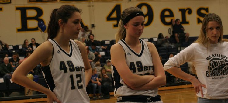 Jessica Taylor, Jenna Wilson number 12, and Mollie Townzen (right) listen in on the huddle