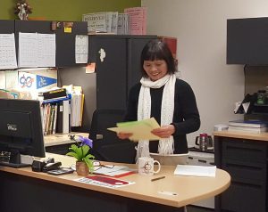 Qui Bui works at her desk with a smile. 