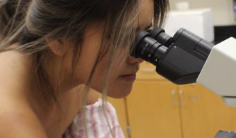 Judy Tran observing specimen in zoology lab.